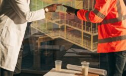 An engineer and worker discussing a digital twin model in a planning room.